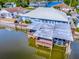 Aerial view of a waterfront home with a large deck and covered boat lift, surrounded by water and greenery at 26608 E Cove Dr, Tavares, FL 32778
