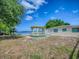 Lakeside view featuring a charming gazebo, picnic table, and lush trees against a blue sky with clouds at 26608 E Cove Dr, Tavares, FL 32778