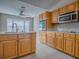 Kitchen with wooden cabinets, stainless steel appliances, tile flooring and a sink with a window at 26608 E Cove Dr, Tavares, FL 32778