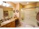 Bathroom featuring a bathtub with glass doors, granite countertops and wood cabinets at 2682 Edwards Ln, The Villages, FL 32162