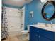 Bright bathroom features blue walls, coordinated vanity, and a bathtub with shower at 27004 Nature View St, Leesburg, FL 34748