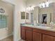 Well-lit bathroom featuring double sinks with wood cabinetry and neutral countertops at 3808 Serena Ln, Clermont, FL 34711