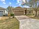 Exterior view of a one-story house with a brick-paver driveway, a two-car garage, and mature trees and shrubs at 3808 Serena Ln, Clermont, FL 34711