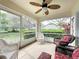 Relaxing screened lanai with ceiling fan, wicker furniture, and a view of the well-maintained yard at 3847 Eversholt St, Clermont, FL 34711