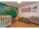 Bright bedroom featuring a crib, unique accent wall, and cozy seating area, creating a playful and inviting space at 4830 Tellson Pl, Orlando, FL 32812