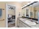 Bathroom with double sinks, granite countertop, and view of a well-lit bedroom at 4955 Ne 124Th Rd, Oxford, FL 34484