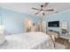 Bedroom featuring wood floors, light blue walls, ceiling fan, and an ensuite bathroom at 4955 Ne 124Th Rd, Oxford, FL 34484