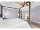 A sunlit main bedroom features a four-poster bed, tray ceiling, ensuite access, and hardwood floors at 4955 Ne 124Th Rd, Oxford, FL 34484