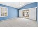 Large, empty room with neutral carpeting and light blue walls and large window at 544 Audrey Ln, The Villages, FL 32162