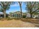 Back exterior featuring a sunroom with large windows and a spacious yard with mature trees at 544 Grand Vista Trl, Leesburg, FL 34748