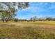 Scenic view of the golf course with golf carts and mature trees under a blue sky at 544 Grand Vista Trl, Leesburg, FL 34748