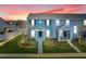 Beautiful townhome featuring a covered porch, colorful architecture, and manicured lawn at dusk at 559 Juniper Springs Dr, Groveland, FL 34736