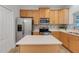 Well-lit kitchen with stainless steel appliances, an island, and wooden cabinets at 559 Juniper Springs Dr, Groveland, FL 34736