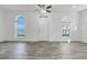 Bright living room boasts arched windows, a ceiling fan, and modern gray wood-look flooring at 559 Juniper Springs Dr, Groveland, FL 34736