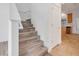 Hallway features wood-look stairs near the kitchen with tan tile floor and wood cabinets at 559 Juniper Springs Dr, Groveland, FL 34736