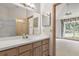 Bathroom with a wood vanity, large mirror, tiled floors, and a doorway view into a carpeted bedroom at 580 Mercers Fernery Rd., Deland, FL 32720