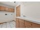 Functional laundry room with white tile flooring, wooden cabinets, and convenient sink at 580 Mercers Fernery Rd., Deland, FL 32720