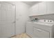 Laundry room with washer, dryer, storage cabinets and white door at 602 Catalina Ct, Lady Lake, FL 32159