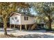 Exterior of a tan raised stilt home with a basketball hoop, gravel yard, stairs and mature trees at 6490 Se 180Th Avenue Rd, Ocklawaha, FL 32179