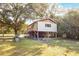 Exterior view of stilt home with wood porch and ladder with mature tree at 6490 Se 180Th Avenue Rd, Ocklawaha, FL 32179