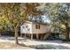 Exterior of a tan raised stilt home with gravel yard, stairs and mature trees at 6490 Se 180Th Avenue Rd, Ocklawaha, FL 32179