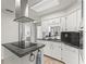 Bright kitchen featuring a center island cooktop, black granite counters, and classic white cabinetry at 701 Brigadoon Cir, Leesburg, FL 34788