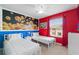 Colorful bedroom with twin beds, bright red accent wall, Lego-themed decor, and natural light from the window at 7581 Oak Spring Ln, Davenport, FL 33837