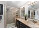 Beautiful bathroom with a glass shower, double sinks with granite counters, and dark cabinetry at 922 Cancun Ct, The Villages, FL 32159