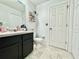 Bathroom with tiled floor, white toilet, black vanity cabinet, and open shelving near the mirror at 1209 Demoiselle St, Groveland, FL 34736