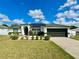 Charming home featuring a well-maintained lawn, a two-car garage, and modern solar panels on the roof at 1209 Demoiselle St, Groveland, FL 34736