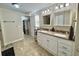 Bathroom featuring double sinks, granite countertops, and well-lit vanity mirrors at 127 Hibiscus Way, Leesburg, FL 34748