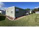 Exterior shot of home with green siding, well-maintained lawn, and garden at 127 Hibiscus Way, Leesburg, FL 34748
