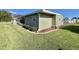 Exterior view features green siding, manicured lawn, and garden beds at 127 Hibiscus Way, Leesburg, FL 34748