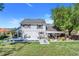Spacious backyard with inground pool, covered patio, green grass, and mature trees under a bright blue sky at 12802 Amber Ave, Clermont, FL 34711