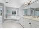 Bright bathroom with white tile, large soaking tub, large mirror, and a window at 12802 Amber Ave, Clermont, FL 34711