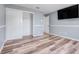 Bedroom with wood-look flooring, white closet doors, and gray walls with white trim and a mounted television at 12802 Amber Ave, Clermont, FL 34711