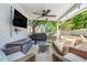 Covered patio with wicker furniture, ceiling fan, TV, and grill overlooking a well-manicured yard at 12802 Amber Ave, Clermont, FL 34711