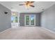 Spacious living room with carpet flooring, ceiling fan, and french door to balcony at 12802 Amber Ave, Clermont, FL 34711