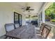 Screened-in patio with ceiling fan, brick tile, and backyard views, including a lounge area and a dining table at 12802 Amber Ave, Clermont, FL 34711