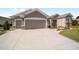 This home boasts a wide driveway, an attached two-car garage, and neutral stucco exterior with manicured lawn at 13146 Se 91St Court Rd, Summerfield, FL 34491