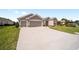 Picture of an attached two-car garage with wide driveway, and lush green front lawn under a bright blue sky at 13146 Se 91St Court Rd, Summerfield, FL 34491