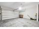 A clean, empty garage with a roll-up door, rolling garbage bins, and gardening equipment is presented at 140 S Zuni Rd, St Cloud, FL 34771