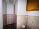 Compact bathroom with tiled walls, toilet, vanity, and overhead cabinets at 15747 Old Highway 50, Clermont, FL 34711