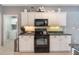 Bright kitchen with white cabinets, stainless appliances, and view to laundry room at 1603 Brookstone Ln, Fruitland Park, FL 34731