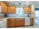 Cozy kitchen featuring wood cabinets, white appliances, and a window overlooking the backyard at 1617 Lakewood Dr, The Villages, FL 32162