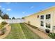 Manicured side yard with a well-maintained lawn, a stone and gravel path, and a pristine white fence at 1622 Valley Falls Way, The Villages, FL 32162