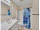 Bathroom with a shower-tub combo, white vanity, blue shower curtain, and light beige walls at 16865 Se 94Th Sunnybrook Cir, The Villages, FL 32162
