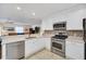Modern kitchen with stainless steel appliances, white cabinets, and an open view into a living room at 16865 Se 94Th Sunnybrook Cir, The Villages, FL 32162
