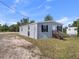 The side view of a single-Gathering home with gray siding, black shutters, and a small wooden porch, surrounded by grass and trees at 17442 Eve Dr, Montverde, FL 34756