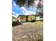Backyard view featuring a yellow home with an outdoor patio perfect for entertaining, set against a blue sky at 224 Westwood Dr, Leesburg, FL 34748